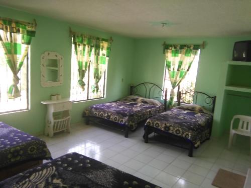 Cette chambre comprend trois lits et deux fenêtres. dans l'établissement HOTEL MONTALVO, à Tezontepec de Aldama