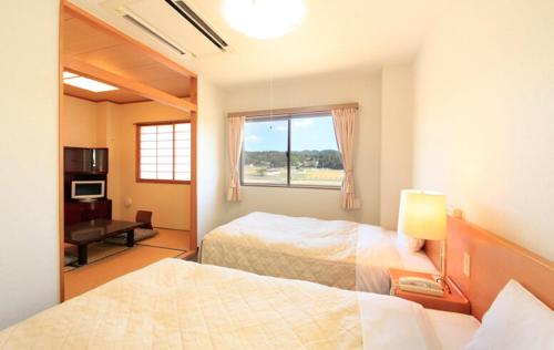 a bedroom with two beds and a window and a desk at Hotel Bouenkaku in Tome