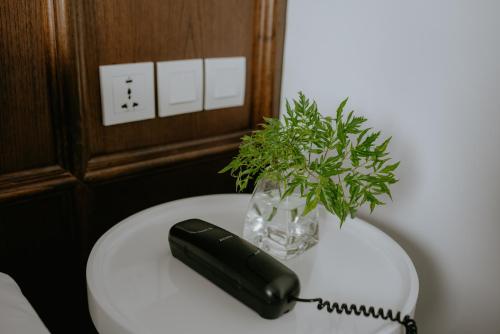 a black phone sitting on a table with a plant at Kampi Hotel Tunjungan - Surabaya in Surabaya