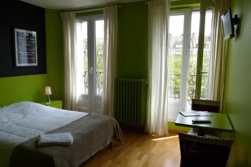 une chambre avec un lit, un bureau et des fenêtres dans l'établissement Hôtel Victor, à Beauvais