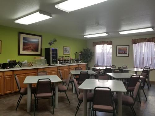 a dining room with tables and chairs and a kitchen at Moab Gateway Inn at Arches Nat'l Park in Moab