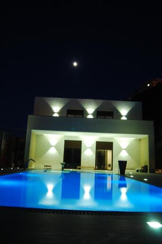 a swimming pool in front of a house at night at Hotel & SPA Riviera Castelsardo in Castelsardo