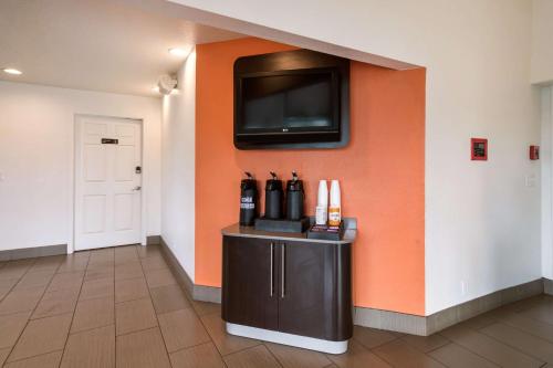 a room with an orange wall with a tv on a wall at Motel 6-Vancouver, WA in Vancouver