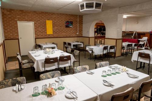 uma sala de jantar com mesas e cadeiras brancas em Gascoyne Hotel em Carnarvon