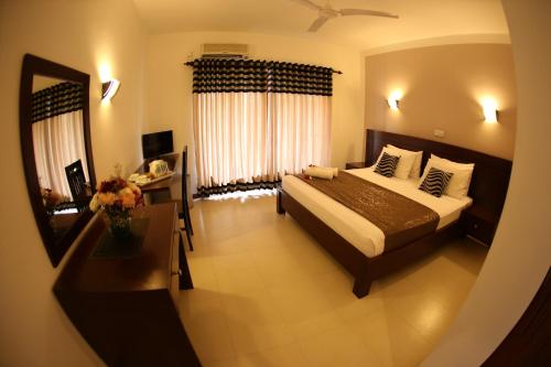 a hotel room with a bed and a mirror at Hotel Shanelo in Negombo