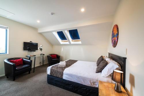a bedroom with a bed and a chair and a television at 123 Motel in Christchurch