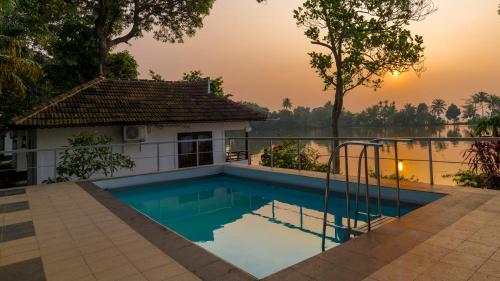 a swimming pool with a view of a river and a house at Warmth Lake Haven in Alleppey