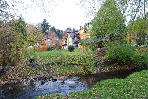 a house with a stream in front of a house at Apart Hotel del Pellin in San Martín de los Andes