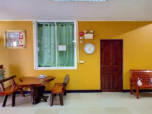 une chambre avec une table et une horloge sur le mur dans l'établissement Peamsuk Sweet Prachin Buri, à Prachin Buri