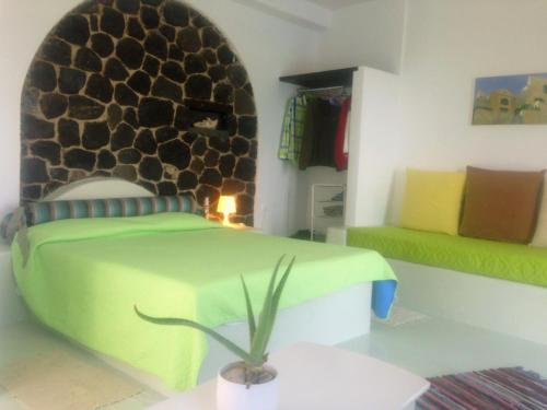 a bedroom with a green bed with a stone wall at Thea Luxury Resort in Fira