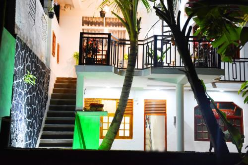 a building with stairs and palm trees in front of it at Indunil place hiriketiya in Dickwella