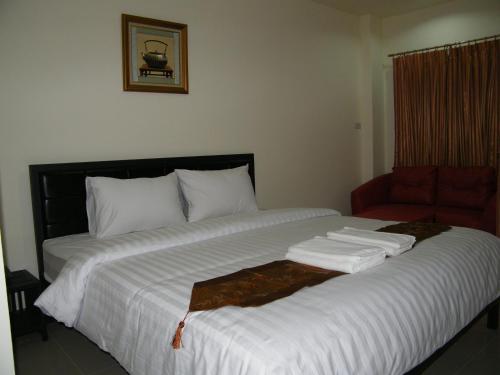 a large bed with white sheets and a red chair at Fundee 1 Mansion in Ubon Ratchathani