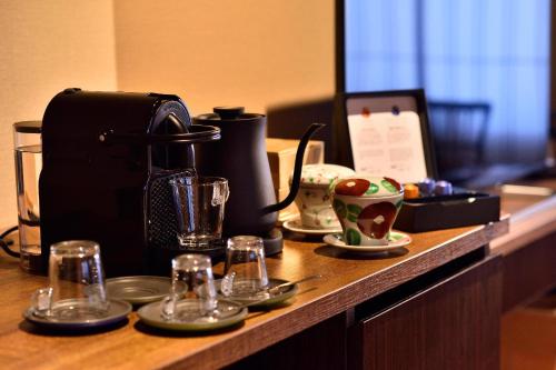 a counter with a coffee maker and cups on it at Muromachi Yutone Kyokoyado in Kyoto