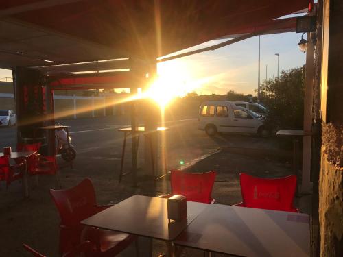 a sun setting in a parking lot with a table and chairs at Hostal Playa Candor in Rota