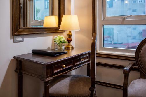 a desk in a room with a lamp and a window at Alisa Hotel & Spa in Hanoi