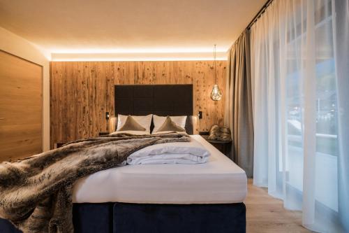 a bedroom with a large bed and a large window at K1 Mountain Chalet - Luxury Apartements in Brunico