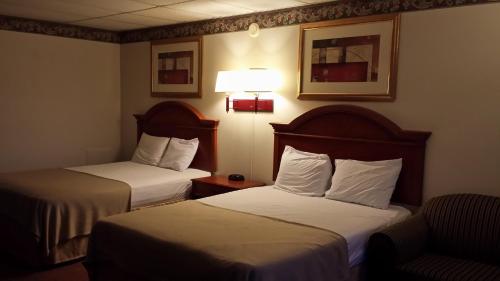 a hotel room with two beds and a chair at Americas Best Value Inn - Palmyra/Hershey in Palmyra