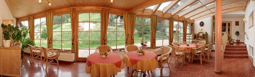 a room with tables and chairs and a large window at Ferienwohnungen Hauser in Sankt Jakob in Defereggen