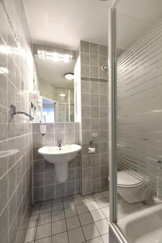 a bathroom with a sink and a toilet and a shower at LAT Hotel & Apartmenthaus Berlin in Eisenhüttenstadt