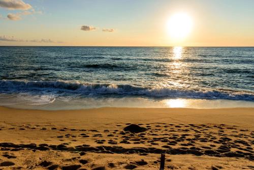 a beach with the sun rising over the ocean at TUISuneo La Conchiglia - Adults Only in Capo Vaticano