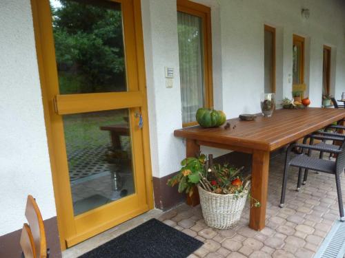 a porch with a wooden table and chairs and a glass door at Ferienwohnungen Hof Heiderich in Beerfelden