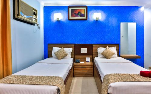 two beds in a room with a blue wall at The Blue Lagoon Hotel Premium in Cuttack
