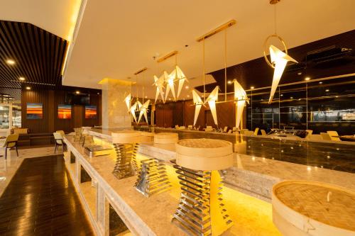 a restaurant with a long counter with chairs and lights at Eagle Hotel in Ha Tinh