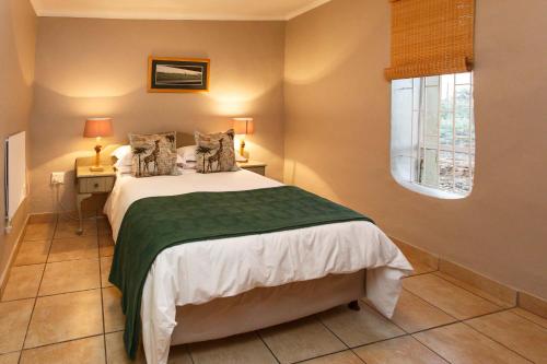 1 dormitorio con 1 cama con manta verde en Hazenjacht Karoo Lifestyle - Die Melkstal, en Oudtshoorn