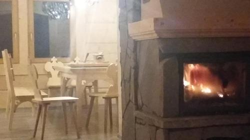 a fireplace in a living room with a table and a dining room at Dom z widokiem na Wierchy - panorama na Tatry - Traditional folk house in Gliczarów Górny
