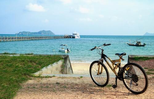 a bike parked next to the ocean with a pier at Baan i Talay Chumphon บ้านไอทะเลชุมพร in Chumphon