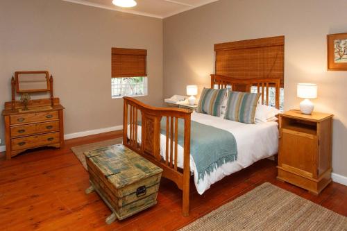 a bedroom with a bed with a wooden headboard and a table at Hazenjacht Karoo Lifestyle - Oom Manus se Huis in Oudtshoorn