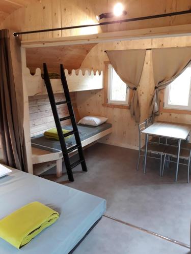 a room with two bunk beds and a table and chairs at Domaine de l'Ours / Camping Lodge in Saint-Urcize