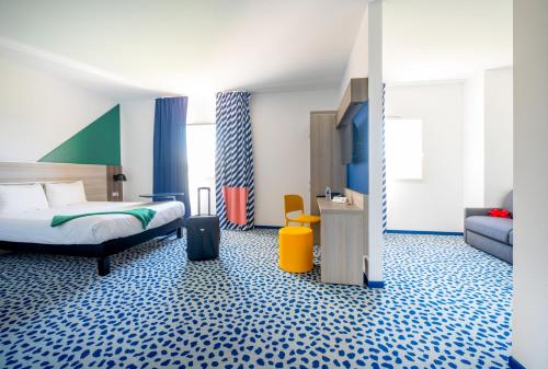 una camera d'albergo con un letto e una valigia di ibis Styles Marseille Plan de Campagne a Les-Pennes-Mirabeau