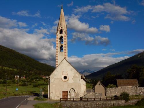 a church with a steeple with a clock on it at Baitin Finferlo in Valdidentro