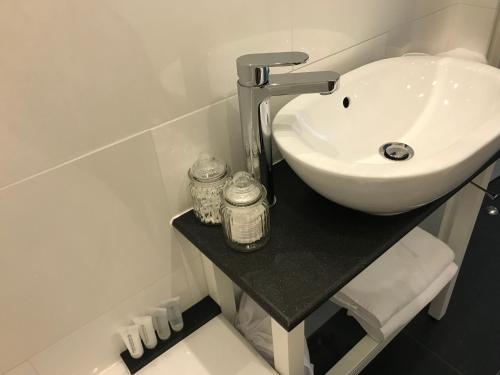 ein Badezimmer mit einem weißen Waschbecken auf einer schwarzen Theke in der Unterkunft Antwerp Business Suites in Antwerpen