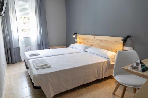 a bedroom with a large white bed and a table at Alda Estella Hostel in Estella