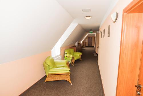 a hallway with two green chairs and a staircase at Penzion Eduard in Františkovy Lázně