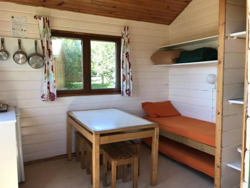 a room with a table and a bench in a tiny house at Domaine de l'Ours / Camping Lodge in Saint-Urcize