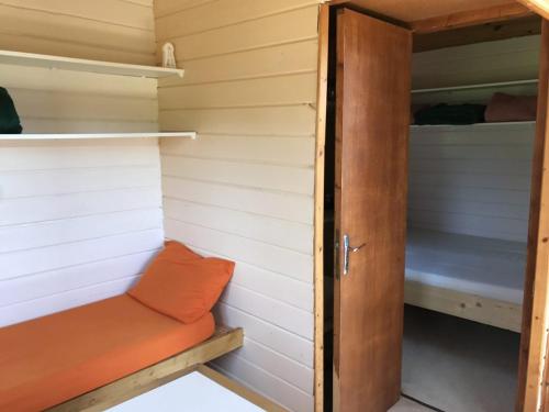 a small closet with an orange seat in a tiny house at Domaine de l'Ours / Camping Lodge in Saint-Urcize