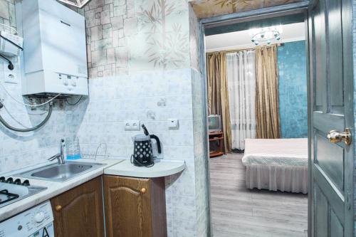 een keuken met een wastafel en een kamer met een bed bij Apartment on Lyul'ky 5 in Lviv