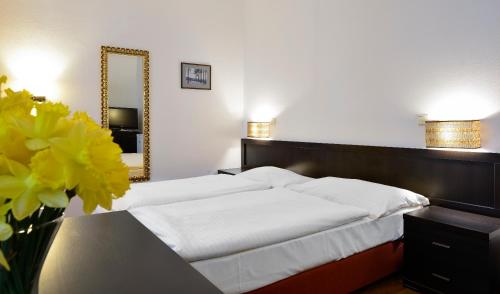 a bedroom with two beds and a mirror and flowers at Apartments Central Park Marienbad in Mariánské Lázně
