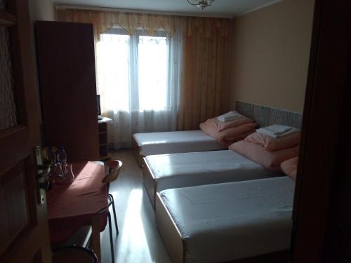 a room with four beds in a room with a window at Zajazd Zagłoba in Widoma