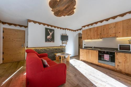 a living room with a red couch and a kitchen at Alpine Residence Villa Adler in San Vigilio Di Marebbe