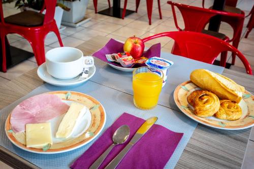 uma mesa com pratos de comida e uma chávena de sumo de laranja em Adams Hotel em Metz