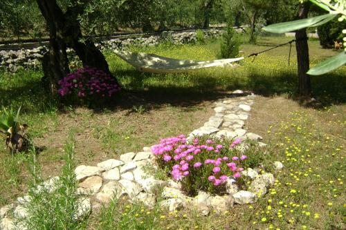 a hammock in a garden with flowers and a bed of rocks at B&B Villa Mediterranea with parking space in Trani