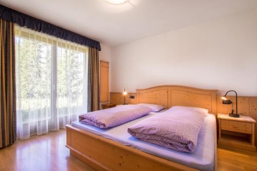 1 dormitorio con 2 camas y ventana grande en Ciasa Isidor, en San Vigilio Di Marebbe