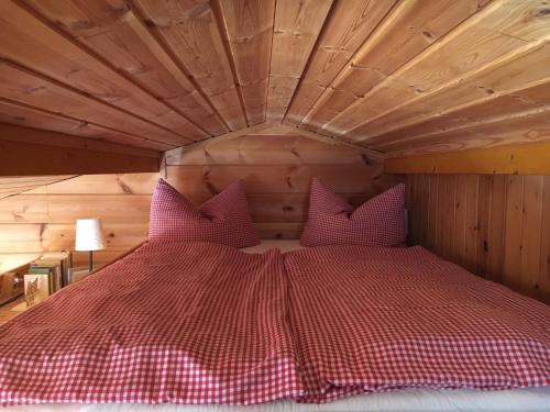 uma cama com almofadas cor-de-rosa num quarto de madeira em Beerenhütte em Kurort Oberwiesenthal