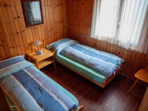 RosswaldにあるChalet Bärgsunnaの木造キャビン内のベッドルーム1室(ベッド2台付)