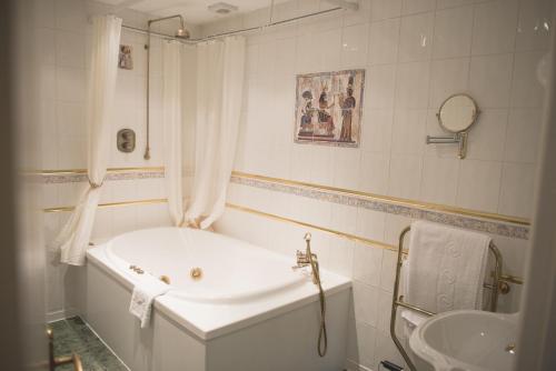 a white bathroom with a tub and a sink at Mere Court Hotel in Knutsford