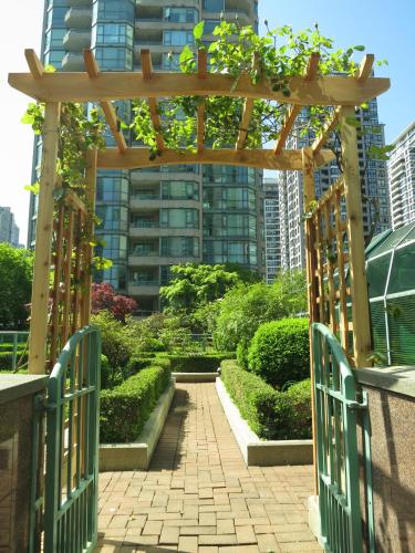 a wooden gate leading to a garden with bushes at Rosedale on Robson Suite Hotel in Vancouver